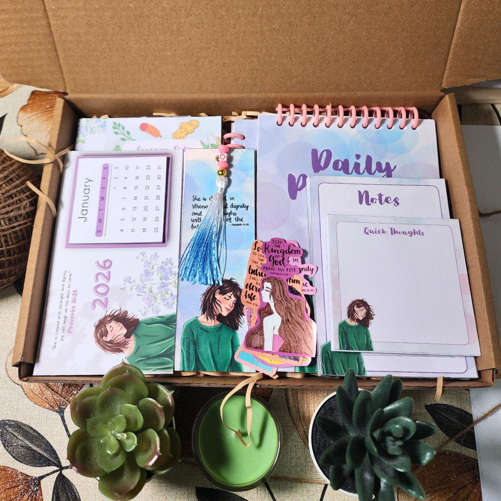 Open cardboard box containing stationery items including notebooks and a calendar.