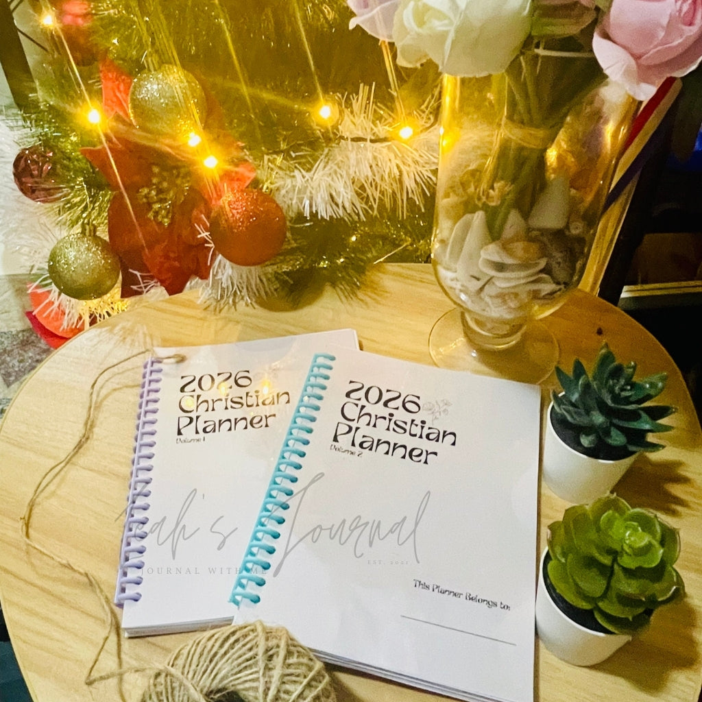 2026 Christian Planner on a table with decorative items including a Christmas tree and flowers.