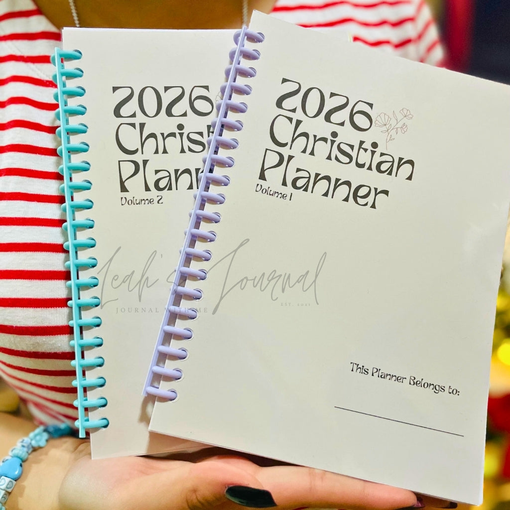 Two '2026 Christian Planner' books held by a person with a striped shirt.