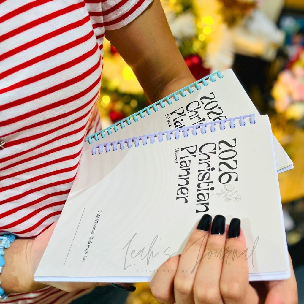 Person holding two 2026 Christian Planner books with a blurred background