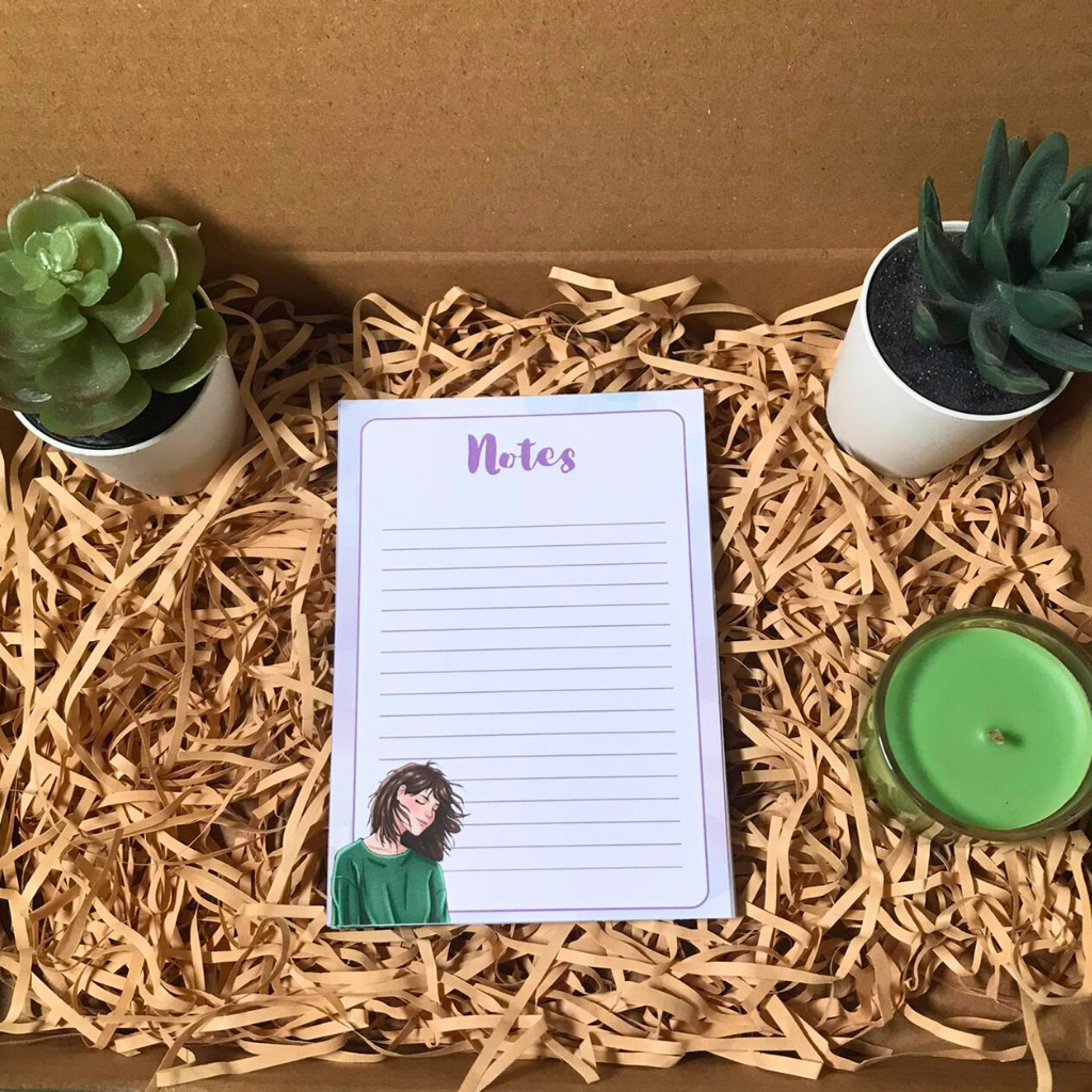 Notepad with a illustration of a person, surrounded by plants and a candle on straw.