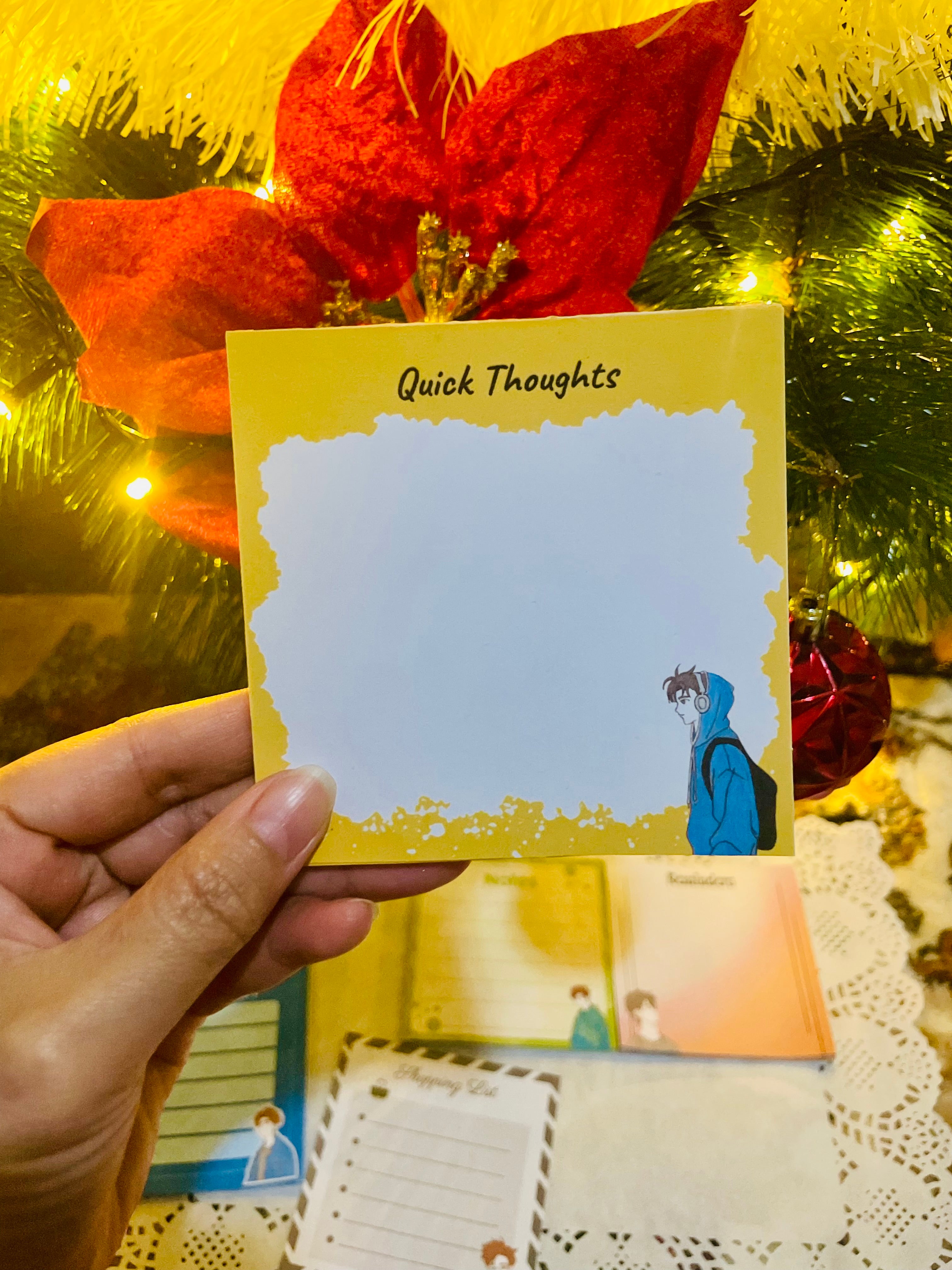 Notebook with 'Quick Thoughts' cover held in front of a decorative background with red flowers and greenery.