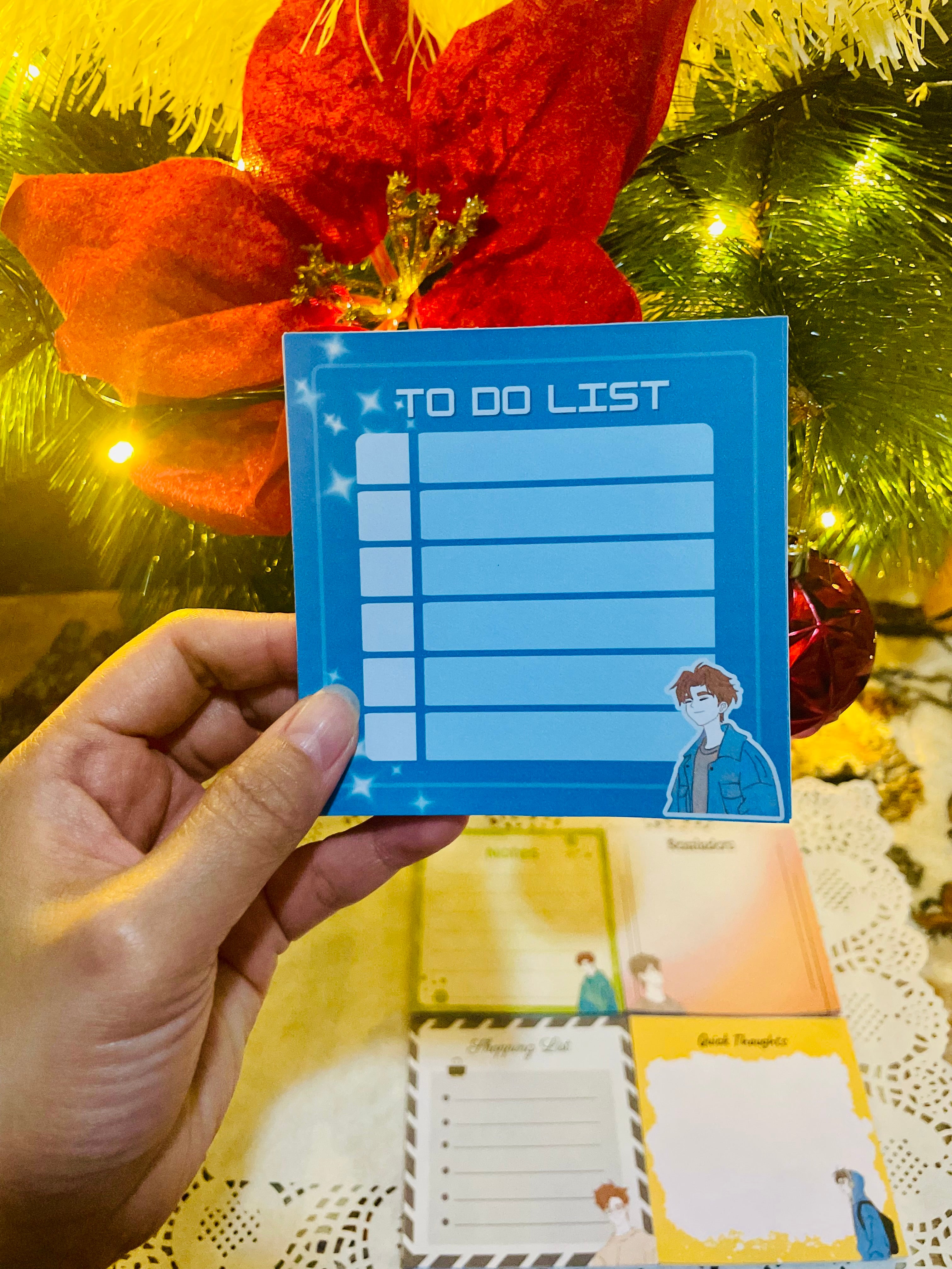 Hand holding a blue 'To Do List' card with Christmas decorations in the background